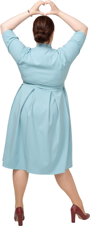 一个穿着蓝色裙子的女人的后视图显示心脏手势