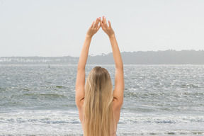 A woman standing on a beach holding her hands up