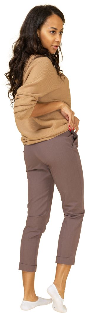 Vista posteriore di tre quarti di una giovane donna dalla pelle scura che si arrotola il pullover