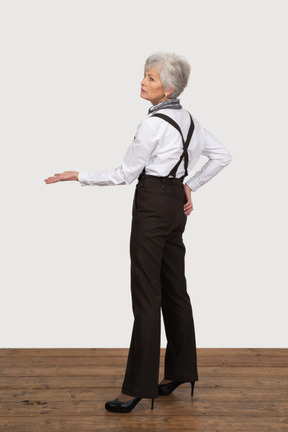 Vista lateral de uma senhora idosa com roupas de escritório estendendo a mão