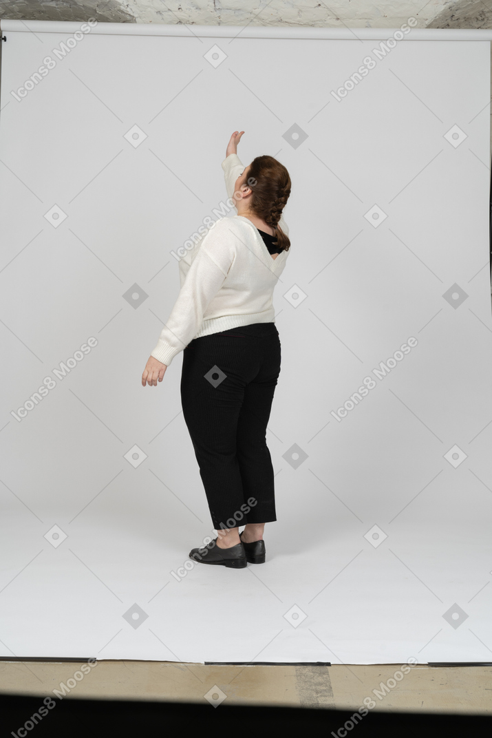 Vue latérale d'une femme dodue dans des vêtements décontractés avec bras levé