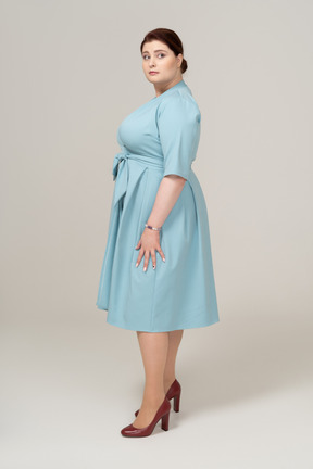 프로필에 서 있는 파란 드레스를 입은 여자