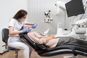 Full-length of a female dentist examining her patient in a hospital cabinet