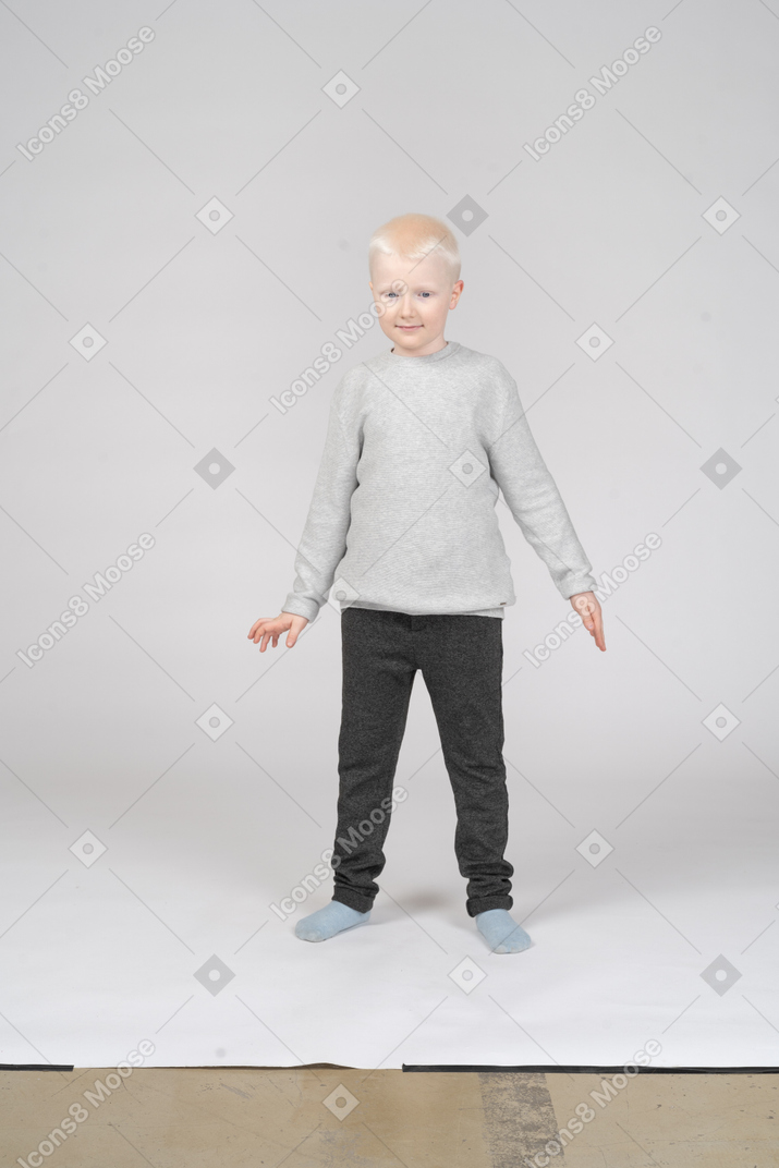 Vista frontal de un niño de pie y sonriendo