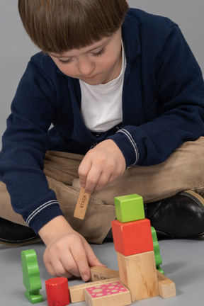 Focused little boy playing with wooden cubes