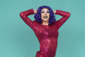 Portrait d'une drag queen souriant avec les mains derrière la tête