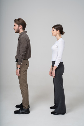 Vista lateral de una joven pareja disgustada en ropa de oficina tejer cejas
