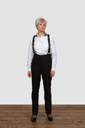Vista frontal de uma mulher idosa com roupas de escritório, parada na sala