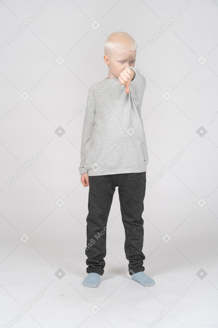 Little boy showing thumb down and looking aside