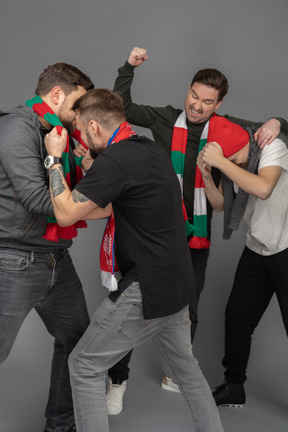 Close-up of four fighting male football fans