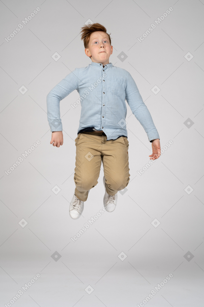 A boy jumping high with bent knees