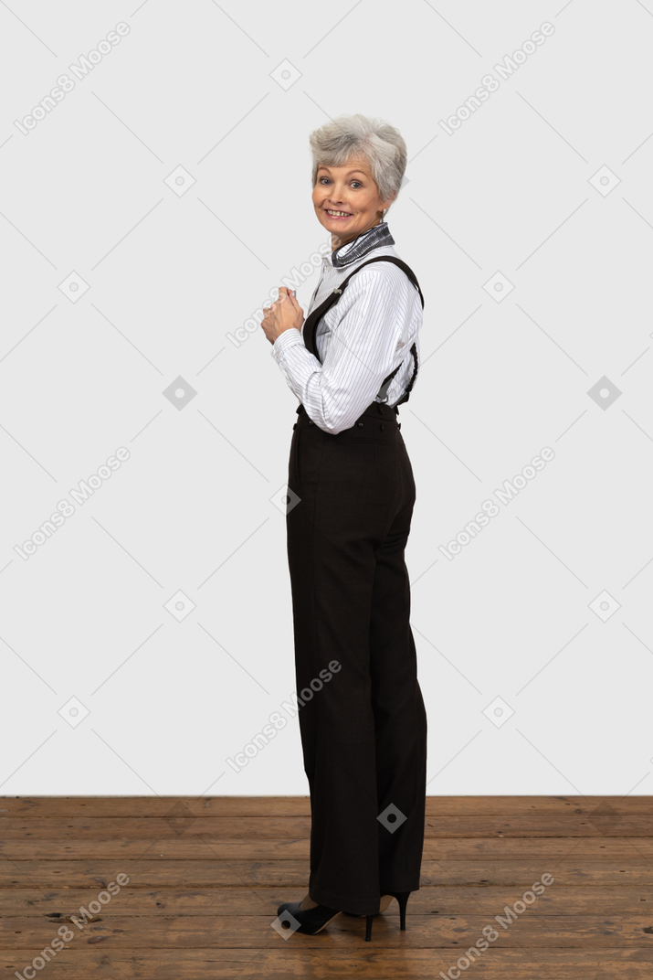 A figura intera se una donna anziana in abiti da ufficio si volta e sorride