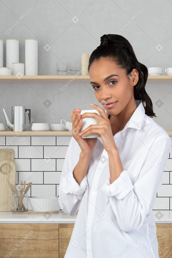 A woman in a white shirt is holding a cup