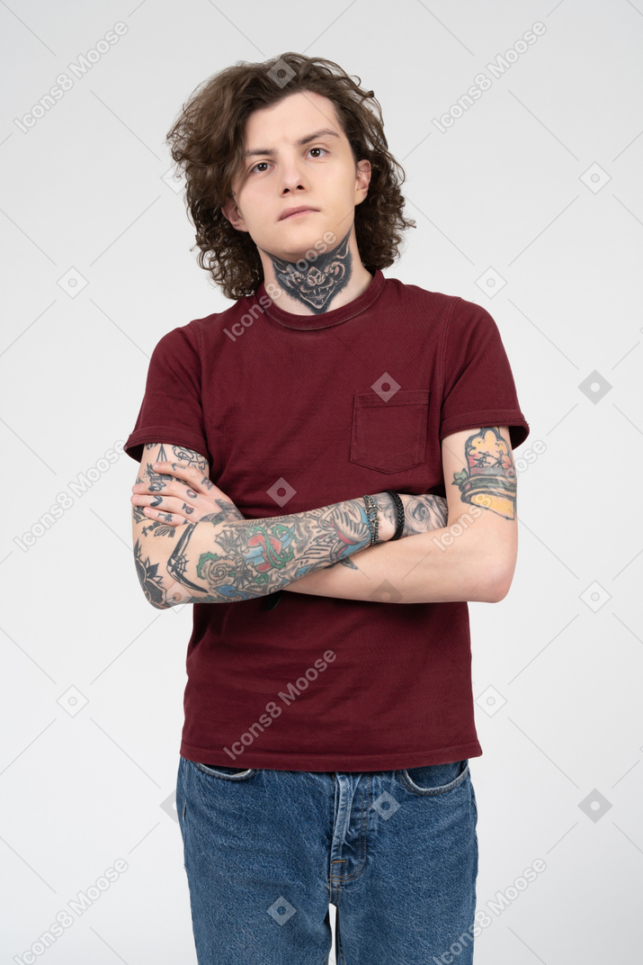 Young tattooed man posing with arms crossed on chest
