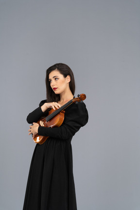 Three-quarter view of a young lady in black dress holding the violin