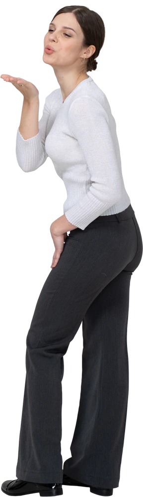 Three-quarter back view of a young woman in office clothing sending an air kiss