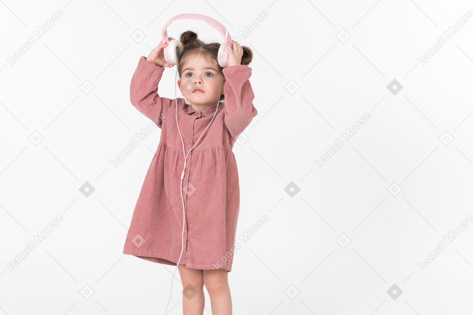 Little girl in pink dress wearing headphones