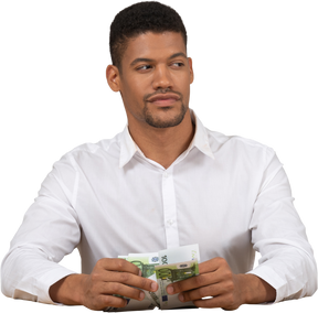 Young man holding money and looking aside