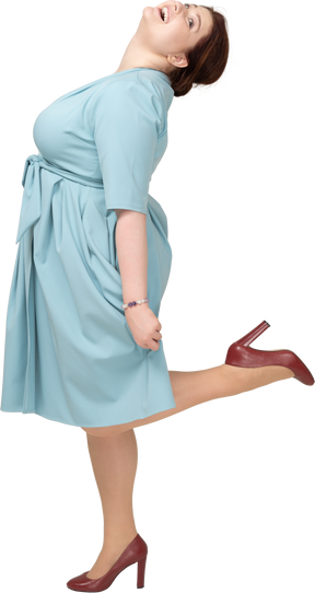 Vista laterale di una donna in abito blu in equilibrio su una gamba