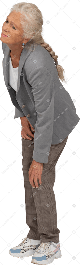 Вид сбоку пожилой женщины в костюме, касающейся ее больного колена