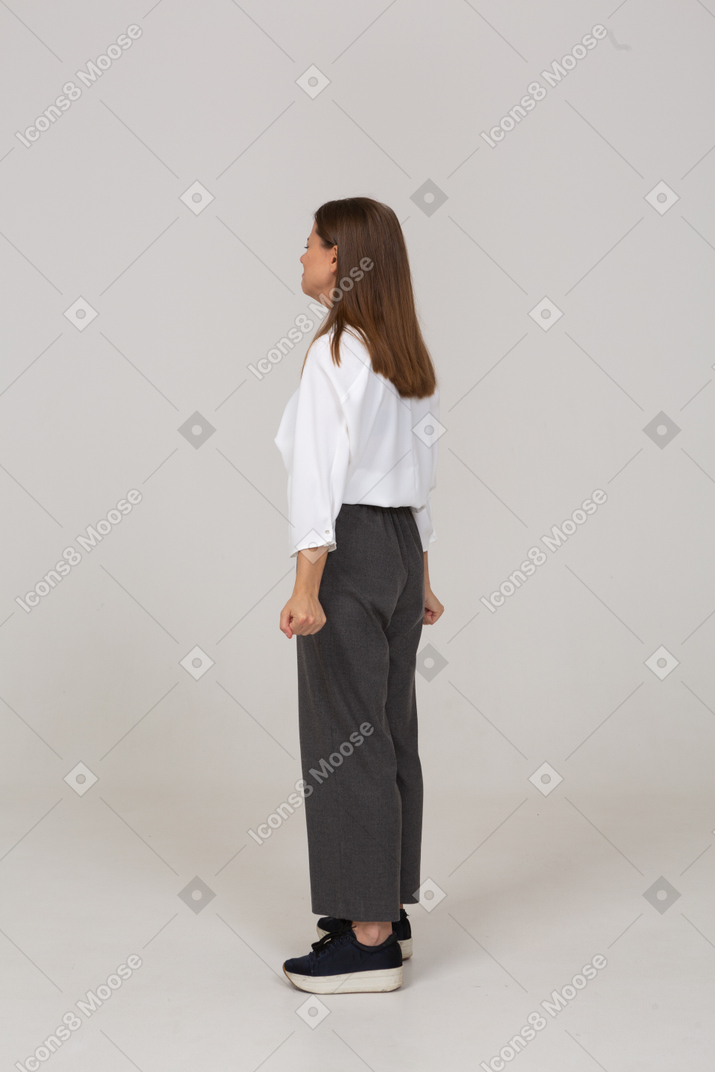 Three-quarter back view of a crying young lady in office clothing clenching fists
