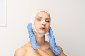 Paciente femenina con manos enguantadas enmarcando su rostro