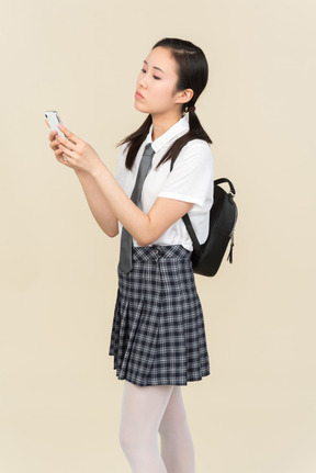 Asian school girl typing on phone