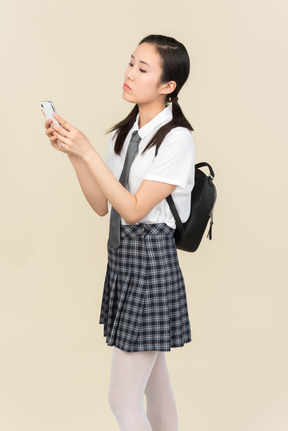 アジアの学校の女の子が電話で入力