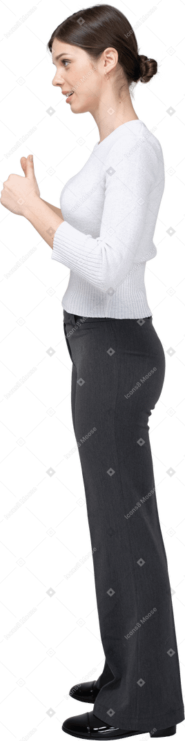 Side view of a woman in black pants and white blouse showing thumbs up
