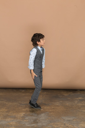 Vista lateral de um menino de terno cinza