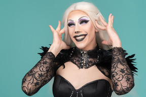 Dragqueen sonriente tocando su sien