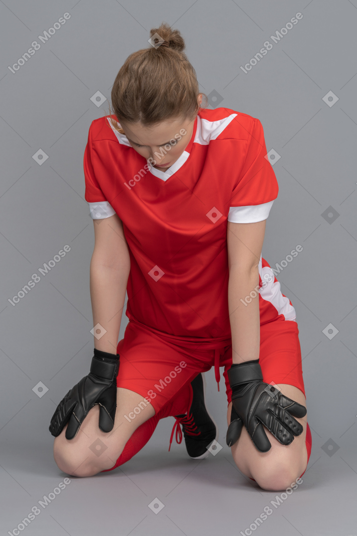 A female goalkeeper is down on her knees