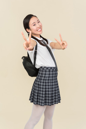 Cheerful asian school girl showing victory