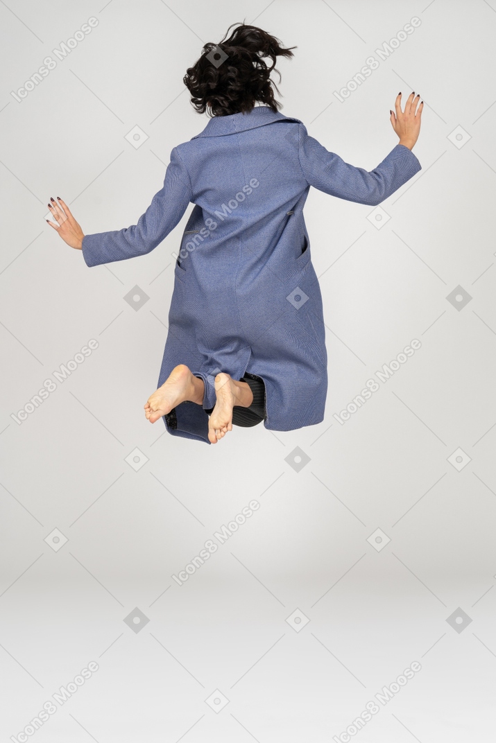女人用折叠腿跳跃的后视图
