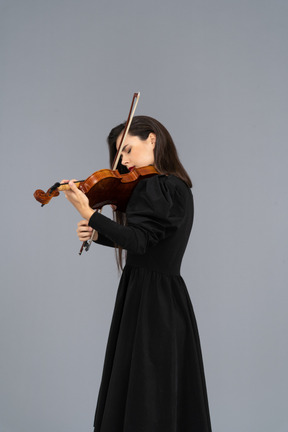 Close-up de uma jovem de vestido preto tocando violino