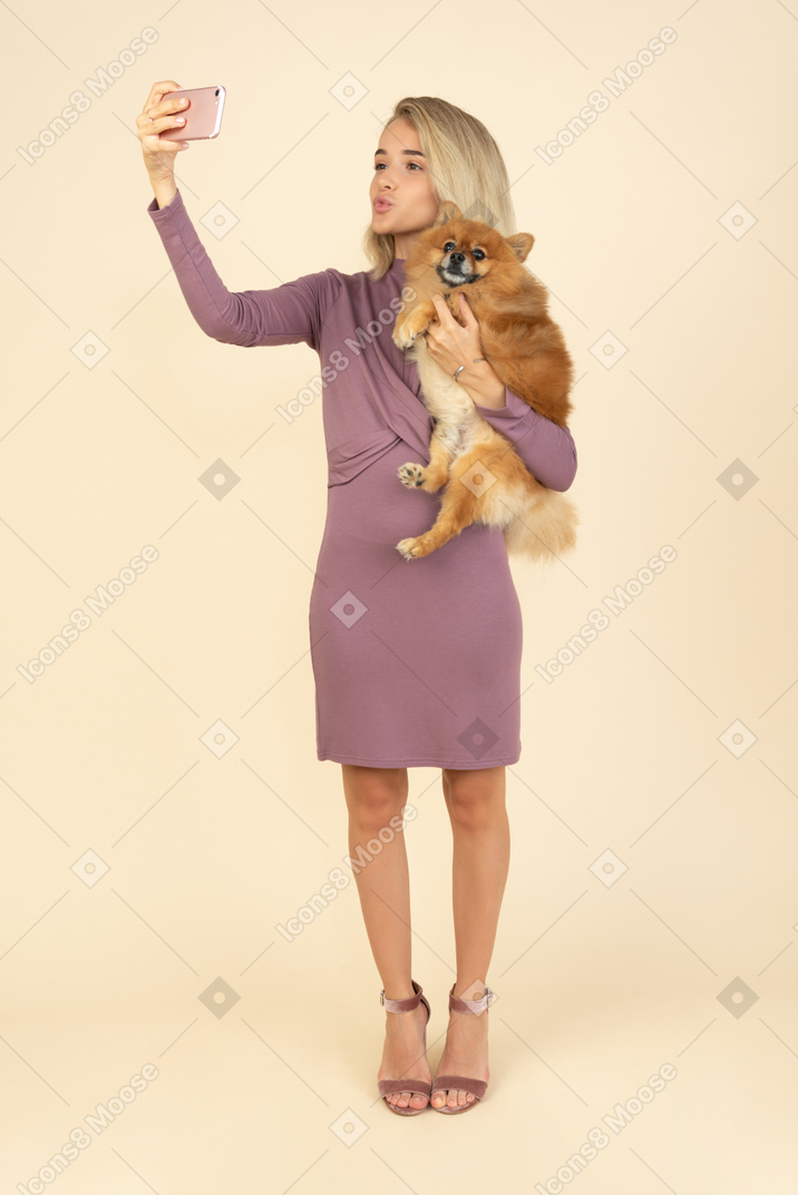 Young girl holding a dog and making a selfie