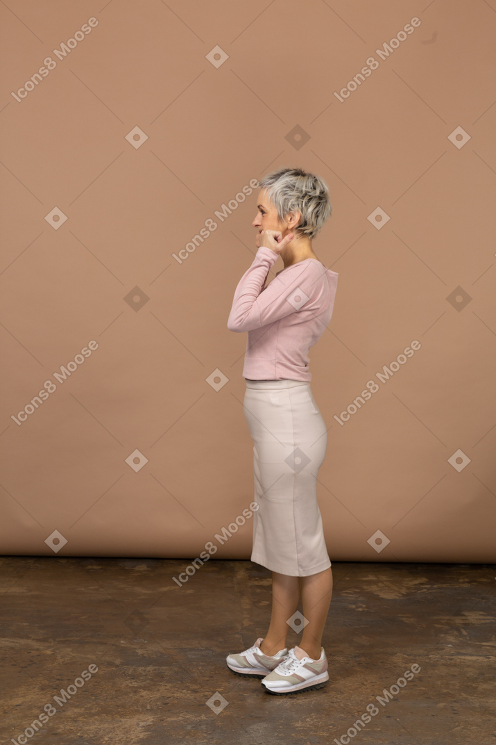 Vista lateral de una mujer en ropa casual poniendo los dedos en la boca