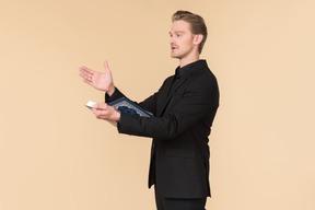 A white man in a fully black suit holding the quran