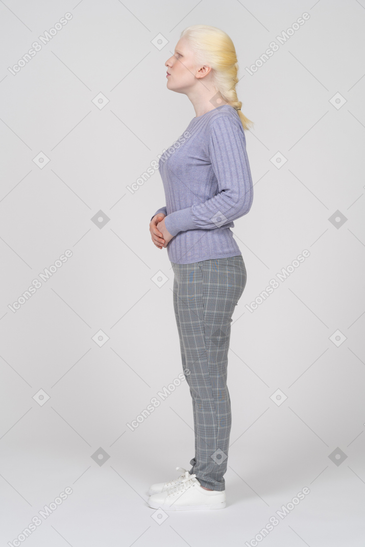 Side view of a woman standing with hands together