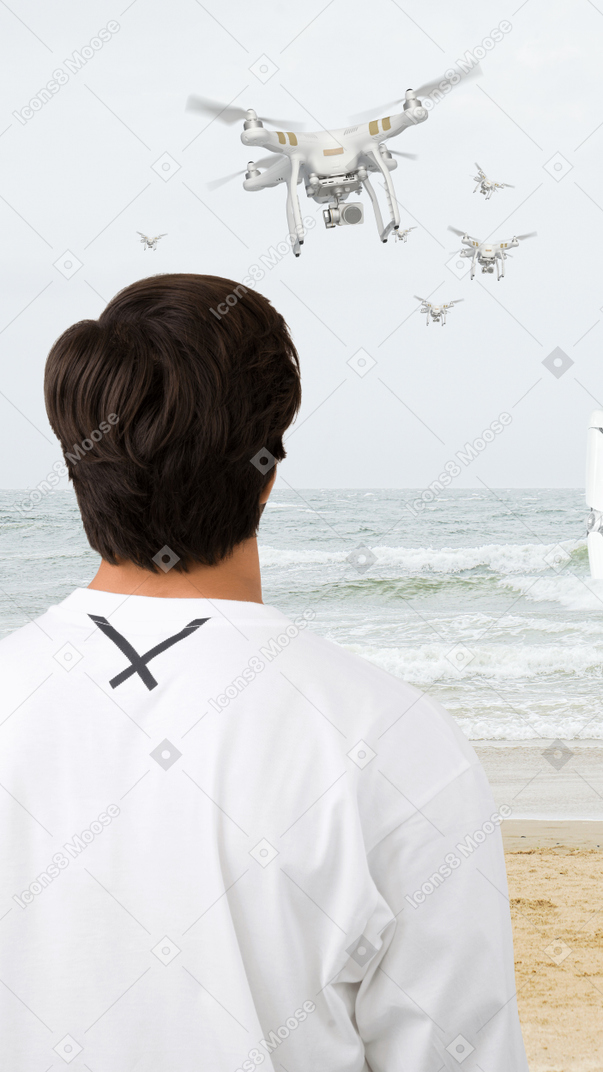 Брюне стоит на берегу моря и наблюдает за летающими дронами