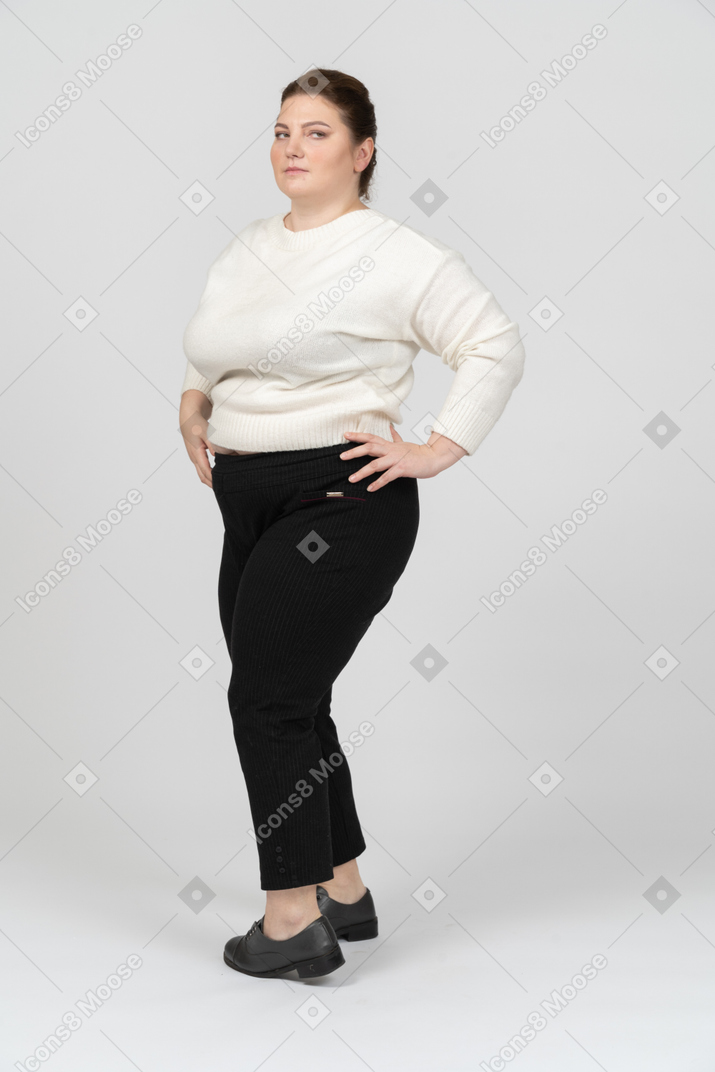 Donna grassoccia in maglione bianco in piedi con le mani sui fianchi