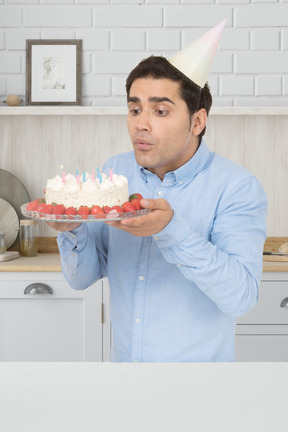 A man in a party hat holding a cake