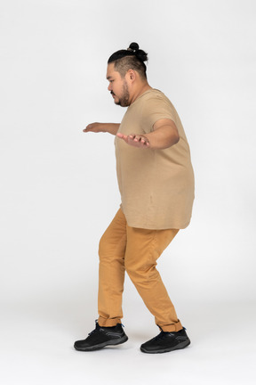 Plump black haired man imitating balancing