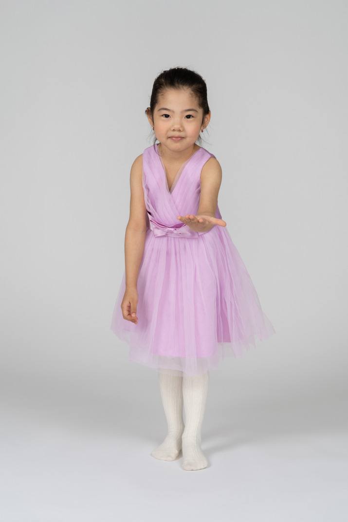 Portrait of a little girl in a tutu dress reaching out her left arm