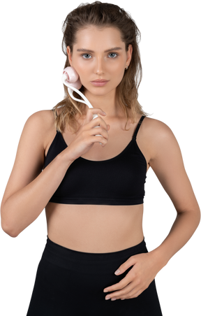 Front view of a young woman massaging her face with a face roller
