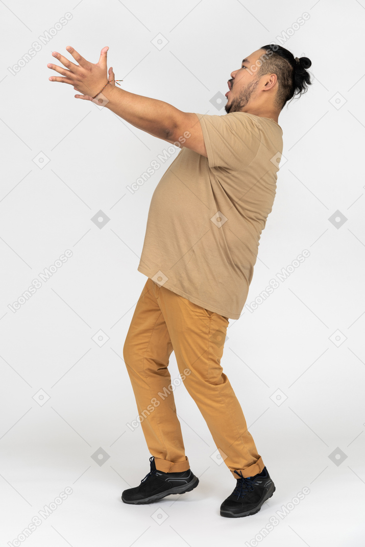 Amazed asian man standing with outstretched arms and open mouth
