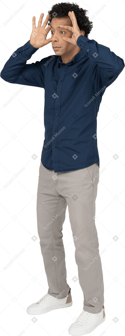 Vista frontal de um homem com roupas casuais olhando através de binóculos imaginários