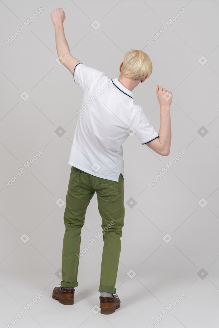 一个快乐的年轻人举起双臂的后视图