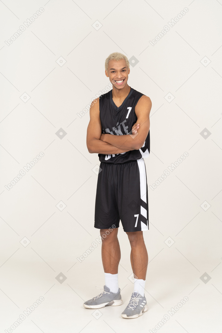 Vista de um jovem sorridente jogador de basquete cruzando os braços