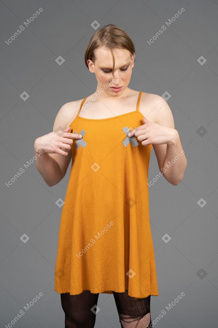 Jovem de vestido laranja cutucando o peito